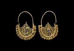Islamic Gold Openwork Earring Pair 17th century AD. A matched pair of gold drop earrings, each a substantial round-section loop and D-shaped plaque formed with filigree scrolls; row of hollow spheres 